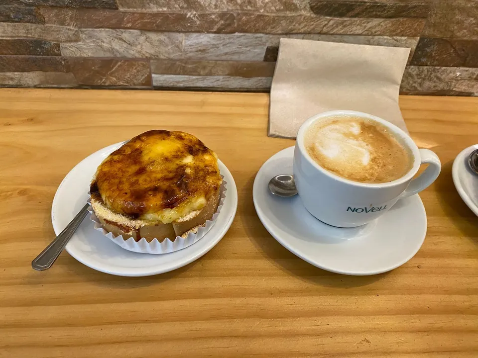 Una crema catalana amb el sucre cremat, al costat d'un cafè
